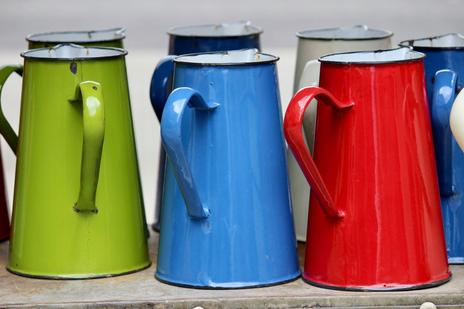 a row of colorful coffee mugs sitting on top of a shelf